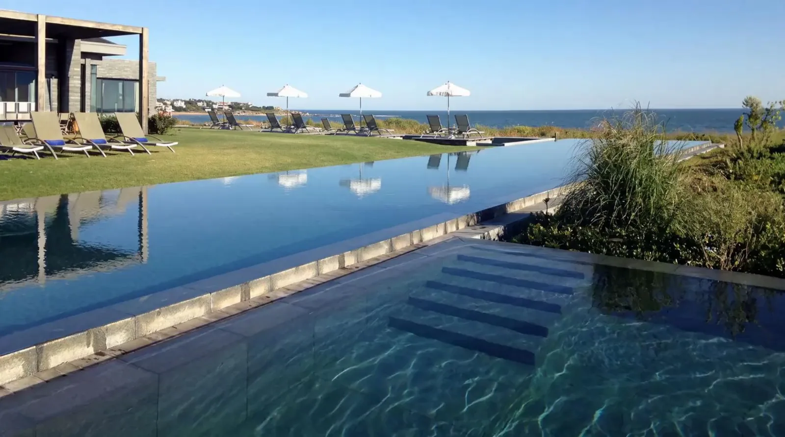 The grey-slate building at Bahía Vik, opening towards the pools and the ocean